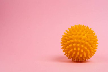 Pembe zemin üzerinde sarı bir masaj iğnesi, düz taban önleme konsepti, hallux valgus, kopyalama alanı