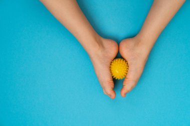 Sarı iğne topu masaj ve fizyoterapi için mavi arka planda çocuk ayağı görüntüsü, hallux valgus önleme ve tedavi konsepti