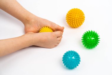 Masaj ve fizyoterapi için renkli iğne topları beyaz arka planda çocuk ayakları görüntüsü, hallux valgus önleme ve tedavi kavramı