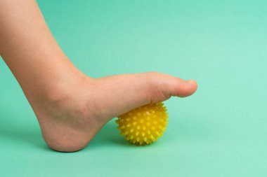yeşil iğne topu masaj ve fiziksel terapi için yeşil arka planda bir çocuk ayağı ile, önleme ve tedavi kavramı ayak valgus