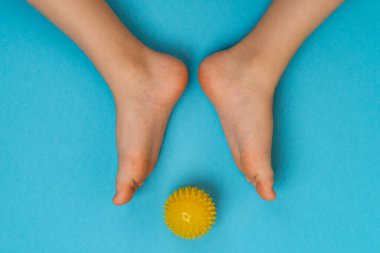 Sarı iğne topu masaj ve fizyoterapi için mavi arka planda çocuk ayağı görüntüsü, hallux valgus önleme ve tedavi konsepti