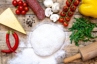 Pizza yapmak için malzemeler, pişirmeden önce, ahşap bir masa üzerinde, üst görünüm, adım adım tarif
