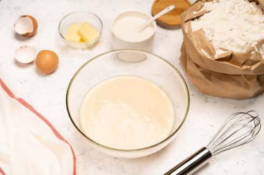 Işık masasında malzemelerle krep yapmak için hamur yapma işlemi yumurta ve un karıştırıcı ile karıştırılır.