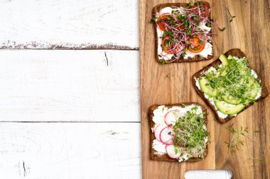 Çeşitli kahvaltı, aperatif kepekli ekmek sandviçleri krem peynirli tost makineleri, turp, avokado, domates, karides, yumurta, arka planda mikro yeşiller, üst görünüm, metin için alan