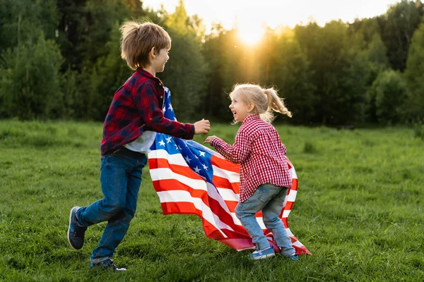 Hermano y hermana con la bandera americana a la luz del sol, niños felices en el Día de la Independencia de EE.UU. — Foto de Stock