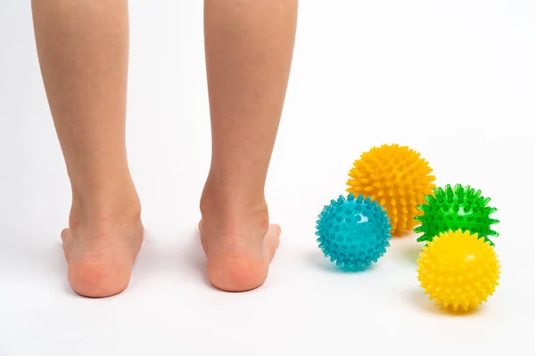 Masaj ve fizyoterapi için renkli iğne topları beyaz arka planda çocuk ayakları görüntüsü, hallux valgus önleme ve tedavi kavramı