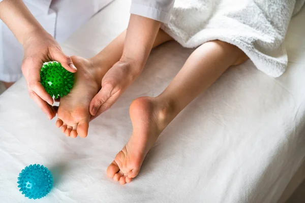 Kobieta robi masaż stóp małej dziewczynce z kulkami do masażu, masaż dziecka, profilaktyka płaskich stóp, osteopatia — Zdjęcie stockowe