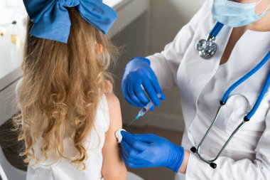 Çocukların aşılanması, doktor randevusundaki küçük bir kız, koluna iğne vurulması,.