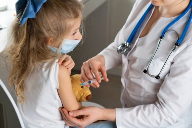 Çocukların aşılanması, doktor randevusundaki küçük bir kız, koluna iğne vurulması,.