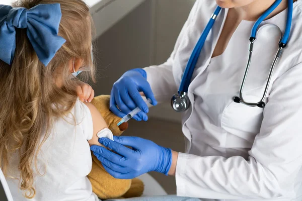 Çocukların aşılanması, doktor randevusundaki küçük bir kız, koluna iğne vurulması,.