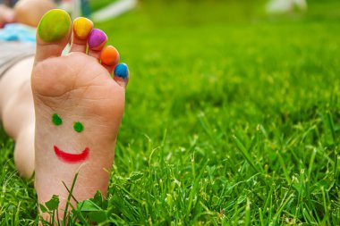 Yeşil çimlerin üzerinde gülümseyen boya desenli çocuk ayakları. Seçici odaklanma.. çocuk