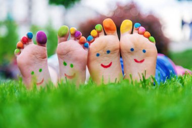 Yeşil çimlerin üzerinde gülümseyen boya desenli çocuk ayakları. Seçici odaklanma. Çocuk