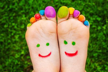 Yeşil çimlerin üzerinde gülümseyen boya desenli çocuk ayakları. Seçici odaklanma. Çocuk