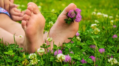 Yeşil çimlerin üzerinde gülümseyen boya desenli çocuk ayakları. Seçici odaklanma. Doğa.