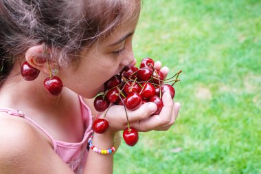 Bir çocuk bahçede kiraz topluyor. Seçici odaklanma. Yiyecek..