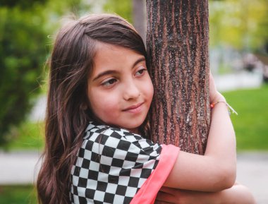 Bir çocuk bir ağaca sarılır - doğayı sever ve korur. Seçici odaklanma. Doğa.