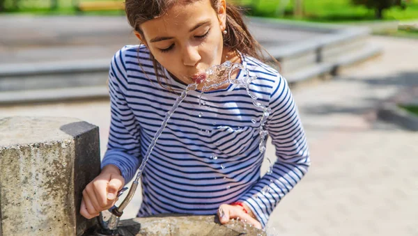 Çocuklar pınardan su içer. Seçici odaklanma. Doğa.
