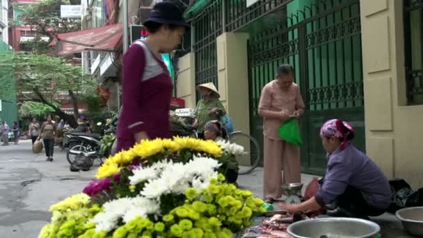 Flores com ao fundo uma mulher vendendo e cortando peixes — Vídeo de Stock