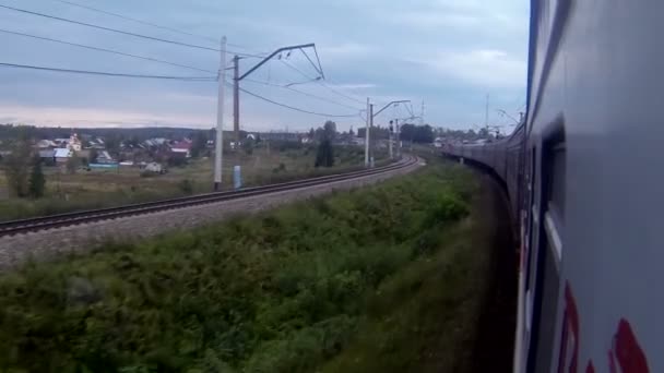 Train in a sharp curve while passing by a village — Stock Video