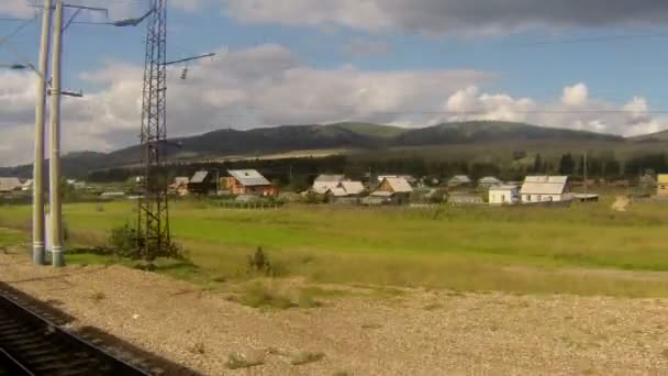 Tåg kör genom en by och station — Stockvideo