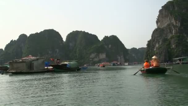 Toeristen in een boottocht door de drijvende dorp in ha long baai — Stockvideo