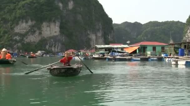 Kid rowing in a boat through a floating fishing village — Stock Video