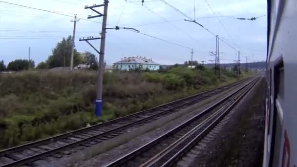 Поїзд проходить через невеликий сільський і залізничний вокзал — стокове відео