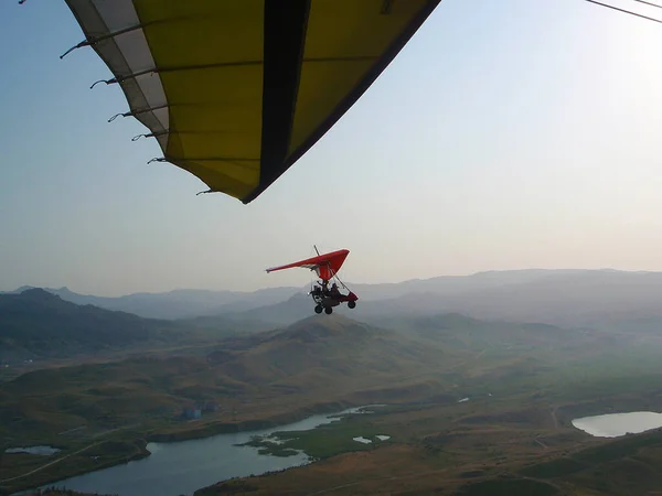 別のハンググライダーから山の上を飛ぶモーターハンググライダーの写真 ロイヤリティフリーのストック写真