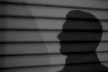 Yakası siyah beyaz önlerine bakan kimliği belirsiz yakışıklı bir adamın gölgesi. 