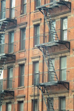 New York 'un merkezinde siyah yangın merdivenleri olan turuncu tuğlalı apartman dairesinin kumlu dış cephesi.