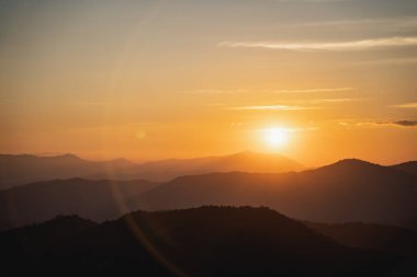 Dağ ve altın sarısı güneşli güneş manzaralı gün batımı. Dağlarda canlı, renkli bir akşam gökyüzü altında. Doğa dağı gökyüzü ve bulutlar günbatımı konsepti