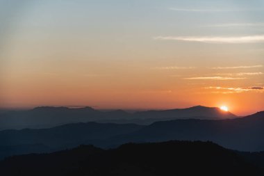 Dağ ve altın sarısı güneşli güneş manzaralı gün batımı. Dağlarda canlı, renkli bir akşam gökyüzü altında. Doğa dağı gökyüzü ve bulutlar günbatımı konsepti