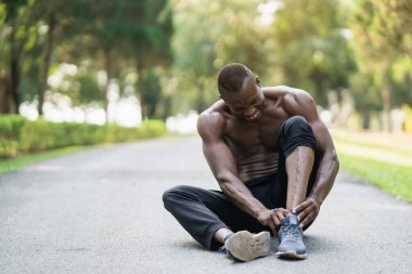 Afrikalı koşucu koşu pistinde oturuyor ve ayak bileğinde ağrı hissediyor. Kopya alanı. Spor sakatlığı konsepti