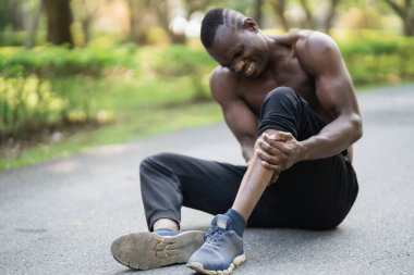 Afrikalı koşucu koşu pistinde oturuyor ve bacağında ağrı hissediyor, kopyalama alanı. Spor sakatlığı konsepti