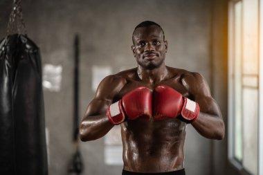 Afrikalı adam spor salonunda antrenman yapıyor ve boks torbası yumruklarını yumrukluyor. Spor salonunda spor adam eğitimi, fitness, boks, başarı, egzersiz ve güç