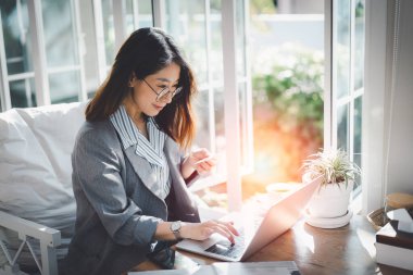 Kredi kartı tutan ve dizüstü bilgisayar kullanan bir kadın. Evde çalışan bir iş kadını. Çevrimiçi alışveriş, e-ticaret, internet bankacılığı, harcama, ev konseptinden çalışma.