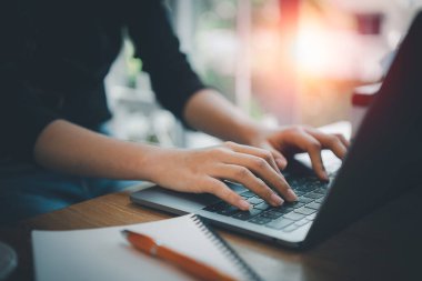 İş kadını laptopta çalışırken kreatif ofiste ya da kafede oturuyor. Kafedeki ahşap masada dizüstü bilgisayarla çalışan genç bir kız..
