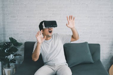 Asyalı adam evde eğlenmek için VR oyunu oynuyor, Asyalı adam tatilde evde neşeli. Mutlu adam metaverse VR teknolojisi konseptini oynuyor..