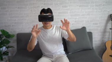 Asyalı adam evde eğlenmek için VR oyunu oynuyor, Asyalı adam tatilde evde neşeli. Mutlu kadın metaverse VR teknoloji konsepti oynuyor.