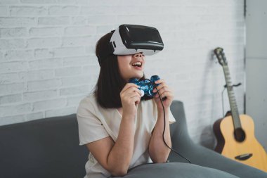 Asyalı kadın evde eğlenmek için video oyunu oynuyor, Asyalı kadın tatilde evde neşeli. Mutlu kadın metaverse VR teknoloji konsepti oynuyor.