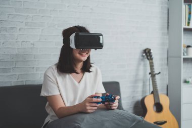 Asyalı kadın evde eğlenmek için video oyunu oynuyor, Asyalı kadın tatilde evde neşeli. Mutlu kadın metaverse VR teknoloji konsepti oynuyor.