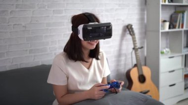Asyalı kadın evde eğlenmek için video oyunu oynuyor, Asyalı kadın tatilde evde neşeli. Mutlu kadın metaverse VR teknoloji konsepti oynuyor.