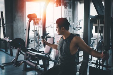 Spor adamı spor salonunda spor makinesi egzersizi yapıyor. Kas eğitimi için Asyalı vücut geliştirme. Spor sağlık spor salonu konsepti