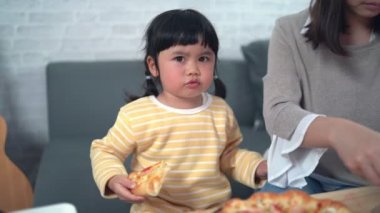 Asyalı anneler ve çocuklar evde faaliyet gösteriyor. Anne çocukları için pizza besleyecek. Çocuklar İtalyan ev yapımı pizza yiyor ve tadıyorlar. Şirin çocuklar rahat evlerinde lezzetli yemekler yiyorlar.