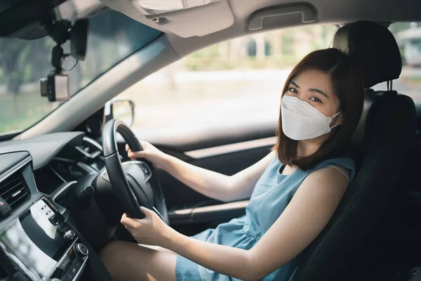 車を運転しながら外科マスクをした幸せなアジア人女性 車を運転して家を出るときにマスクをしていました — ストック写真