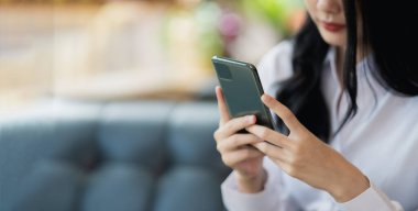 Asyalı kadın cep telefonu mesajı ya da mesajı tutuyor. İş kadını interneti taramak, e-kitap okumak, hisse senetlerini satmak için modern akıllı telefon kullanıyor. Boşluğu kopyala.