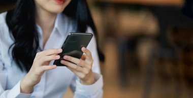 Asyalı kadın cep telefonu mesajı ya da mesajı tutuyor. İş kadını interneti taramak, e-kitap okumak, hisse senetlerini satmak için modern akıllı telefon kullanıyor. Boşluğu kopyala.
