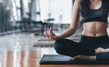 spor yapan Asyalı kadın yoga dersi alıyor, nefes alıyor, meditasyon yapıyor Ardha Padmasana egzersizi yapıyor, spor salonunda egzersiz yapıyor.