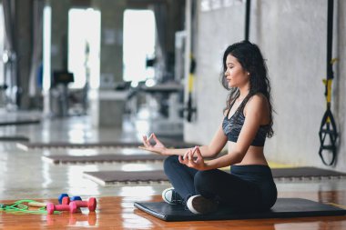 spor yapan Asyalı kadın yoga dersi alıyor, nefes alıyor, meditasyon yapıyor Ardha Padmasana egzersizi yapıyor, spor salonunda egzersiz yapıyor.