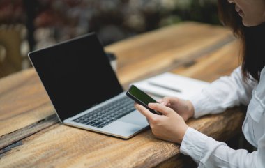 Kadın cep telefonu mesajı ya da mesajı tutuyor. İş kadını web 'e, çalışan dizüstüne ve hisse senetlerine göz atmak için akıllı telefon kullanıyor.